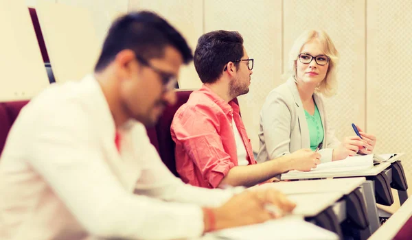 Group of students with notebooks in lecture hall — Stock Photo, Image