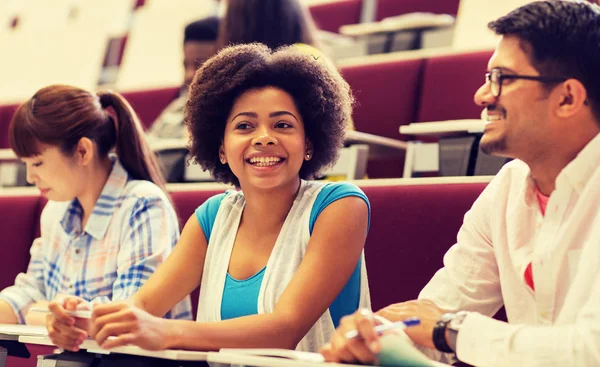 Grupo de estudiantes con cuadernos en la sala de conferencias — Foto de Stock