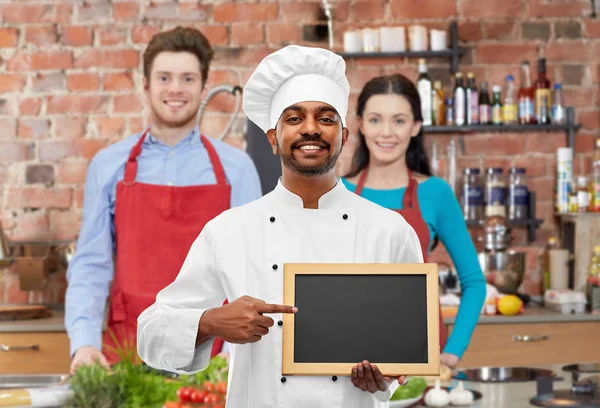 Glücklicher indischer Koch mit Tafel beim Kochkurs — Stockfoto