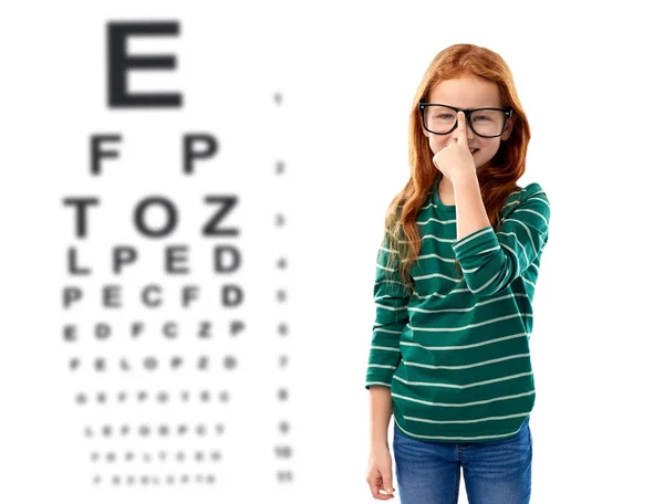 Chica de pelo rojo en gafas sobre la carta de prueba del ojo —  Fotos de Stock