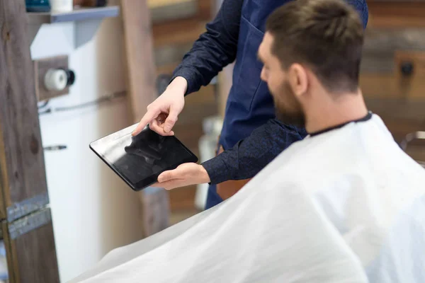 Barbero que muestra la PC tableta al cliente en la barbería —  Fotos de Stock