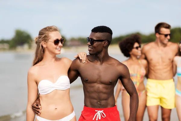 Glada vänner eller par kramas på sommaren stranden — Stockfoto