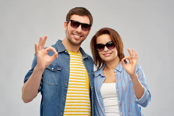 Feliz pareja en gafas de sol mostrando ok signo de mano — Foto de Stock