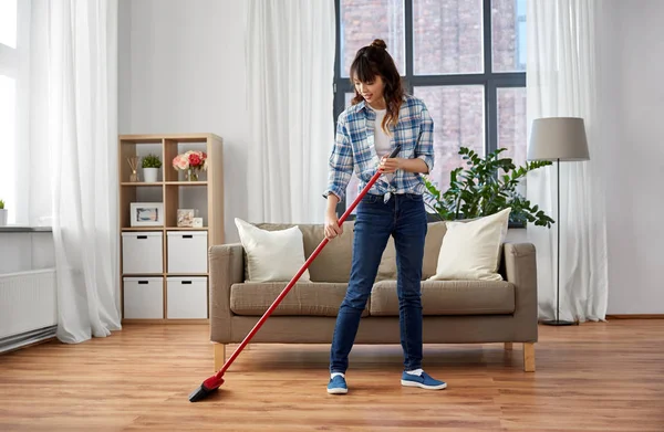 asian woman with broom sweeping floor and cleaning