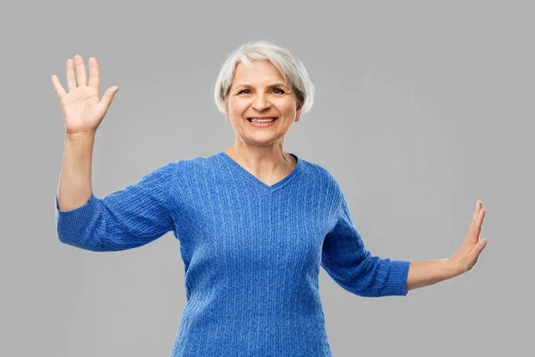 Sorridente donna anziana toccare qualcosa di immaginario — Foto Stock