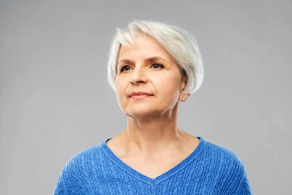 Portret van senior vrouw in blauwe trui over grijs — Stockfoto