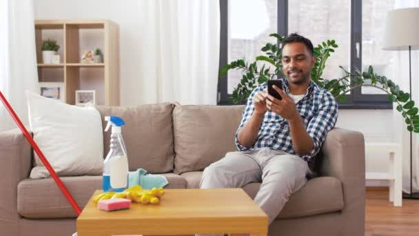 Pria indian menggunakan smartphone setelah membersihkan rumah — Stok Video