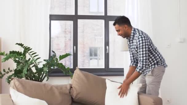 Indiana homem arranjando sofá almofadas em casa — Vídeo de Stock