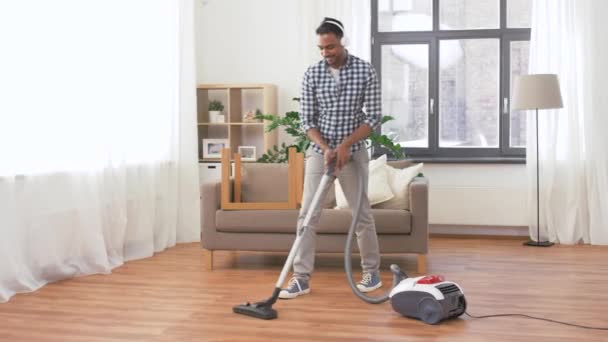 Man in headphones with vacuum cleaner at home — Stock Video