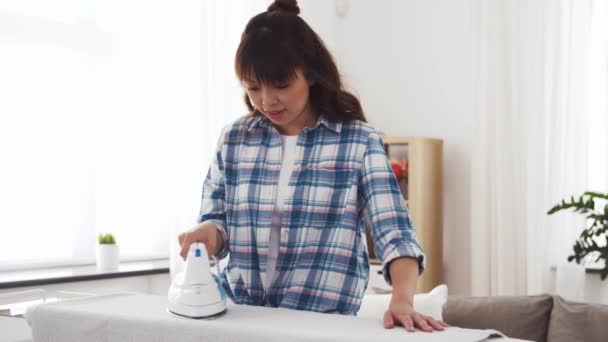 Mujer asiática planchando ropa de cama en casa — Vídeos de Stock