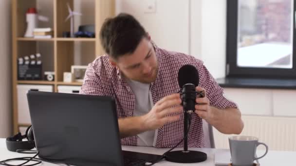 Человек в наушниках с ноутбуком говорит с микрофоном — стоковое видео
