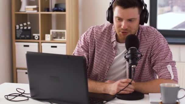 Człowiek w słuchawkach z laptopem przemawia do mikrofonu — Wideo stockowe