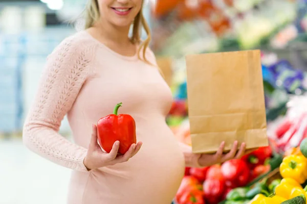 Mujer embarazada comprando verduras en la tienda de comestibles — Foto de Stock