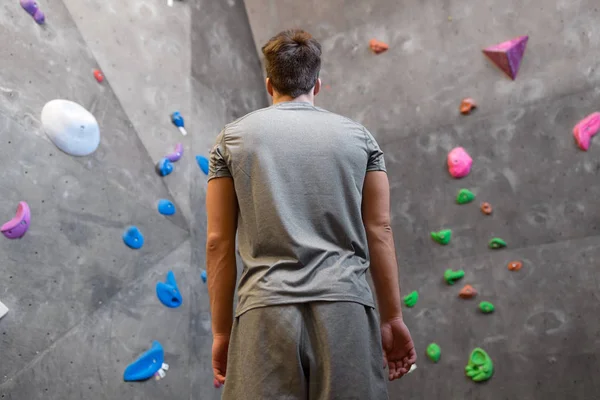 Jovem na parede de escalada interior no ginásio — Fotografia de Stock