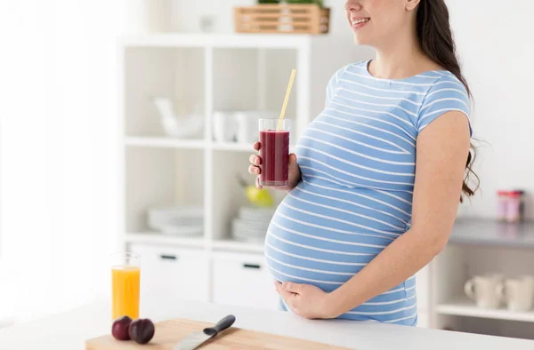 Mujer embarazada bebiendo batido de frutas en casa — Foto de Stock
