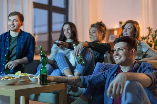 Amici felici con bevande guardando la tv a casa — Foto Stock