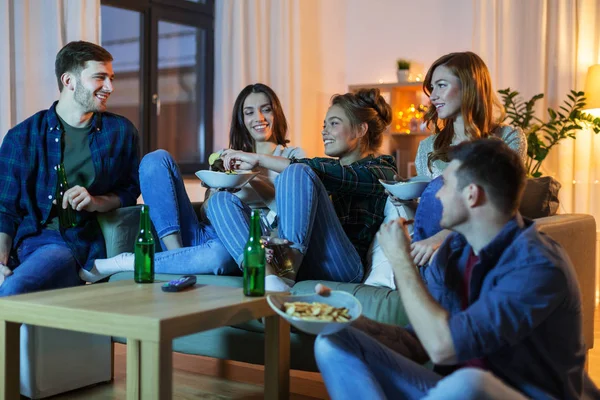 Przyjaciele z napojami i przekąskami, oglądania telewizji w domu — Zdjęcie stockowe