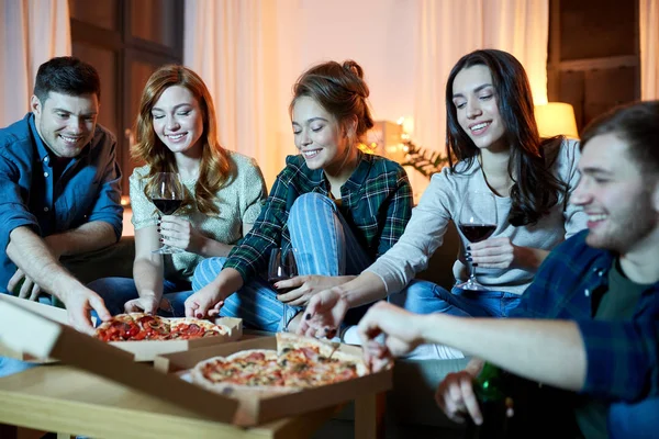 Amici mangiare pizza e bere vino rosso a casa — Foto Stock