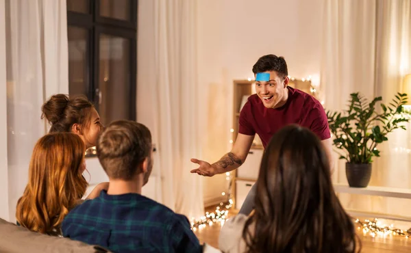 Amis jouer à deviner jeu à la maison dans la soirée — Photo