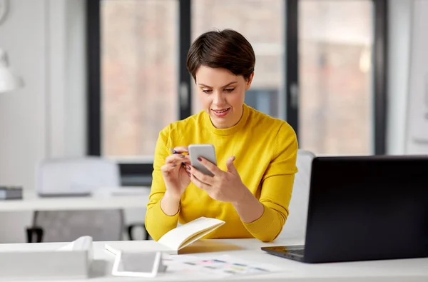 Diseñador ui sonriente usando teléfono inteligente en la oficina — Foto de Stock