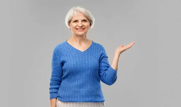 Donna anziana che tiene qualcosa a mano vuota — Foto Stock