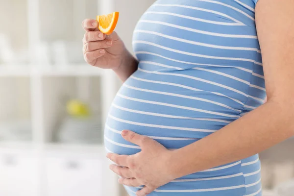 Close-up de mulher grávida comendo laranja em casa Fotos De Bancos De Imagens Sem Royalties