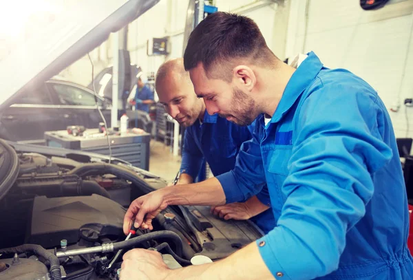 Hombres mecánicos con llave inglesa reparación de coches en el taller —  Fotos de Stock