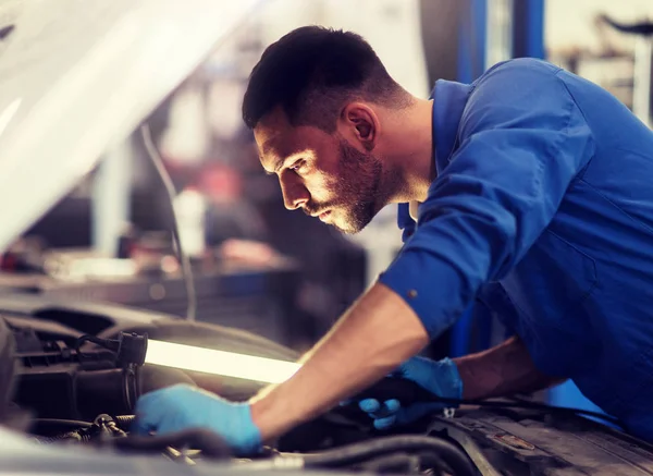 Mecánico hombre con lámpara de reparación de coches en el taller — Foto de Stock