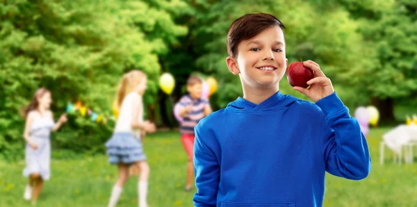 Mosolygós fiú piros almával születésnapi partiján — Stock Fotó