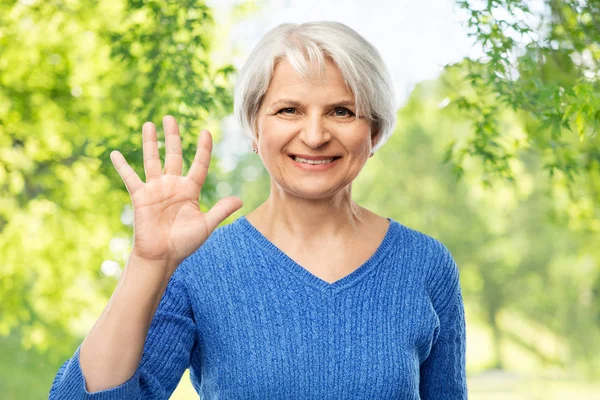 Gülen yaşlı kadın avuç içi veya beş parmak gösteren — Stok fotoğraf