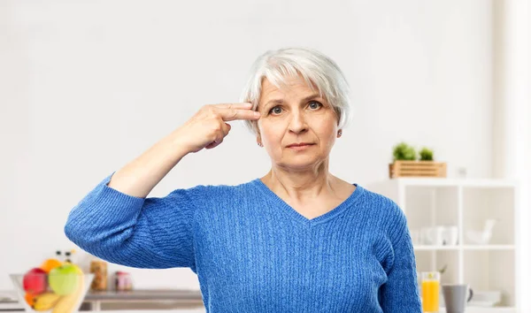 Donna anziana che fa gesto pistola dito in cucina — Foto Stock