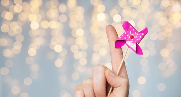 Close up de mão segurando brinquedo pinwheel sobre luzes — Fotografia de Stock