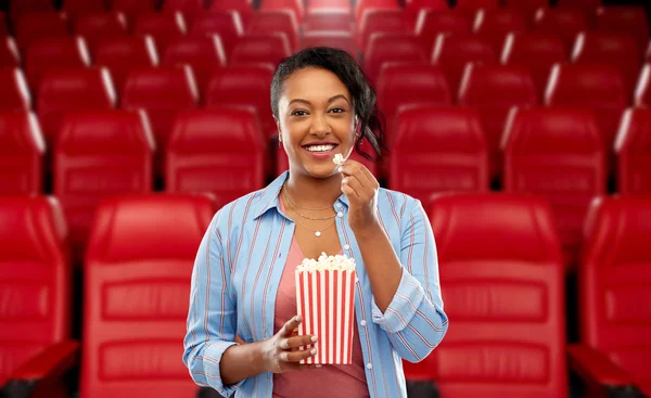 African woman eating popcorn at movie theater — Stock Photo, Image