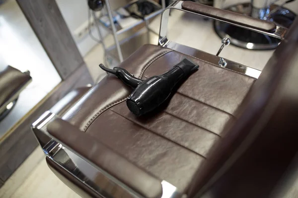 Secador de cabelo no assento da cadeira de couro na barbearia — Fotografia de Stock