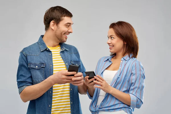 Счастливая пара со смартфонами разговаривают — стоковое фото