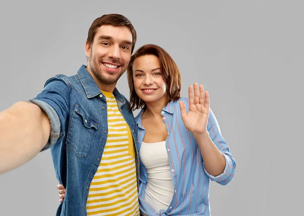 Gelukkig paar nemen selfie over grijze achtergrond — Stockfoto