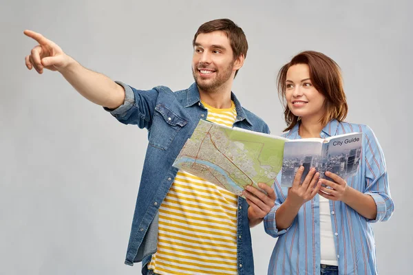 Happy couple of tourists with city guide and map — Stock Photo, Image