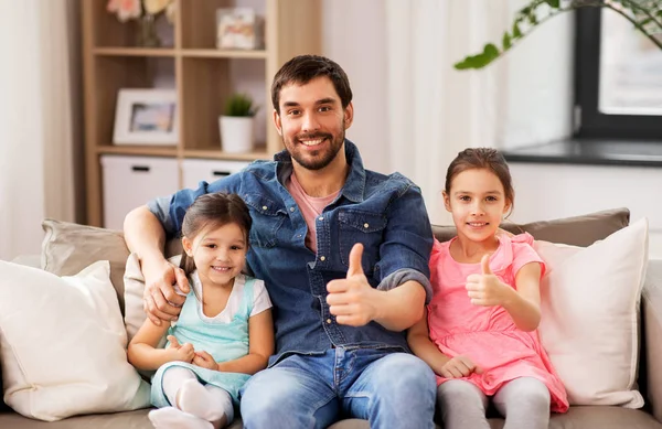 Отец с дочерьми, показывающими большие пальцы дома — стоковое фото