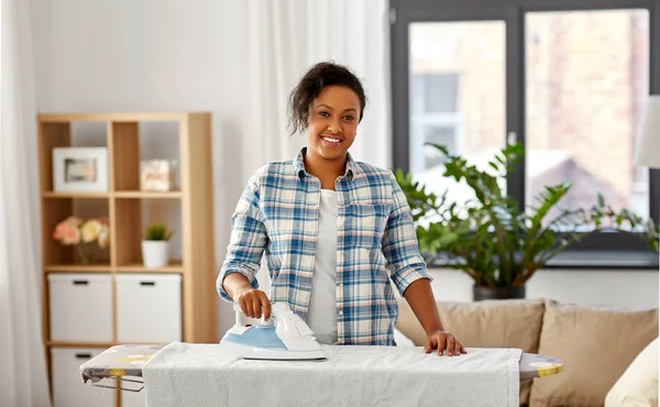 Afrikanerin bügelt Bettwäsche zu Hause — Stockfoto