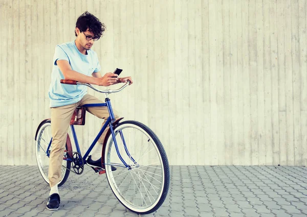 Hombre con teléfono inteligente y bicicleta de engranaje fijo en la calle —  Fotos de Stock