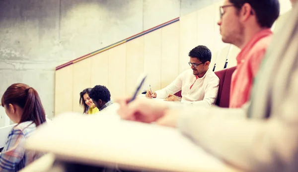 Grupp studenter med anteckningsböcker i föreläsningssalen — Stockfoto