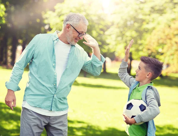 Old man and boy with soccer ball making high five — Stock Photo, Image