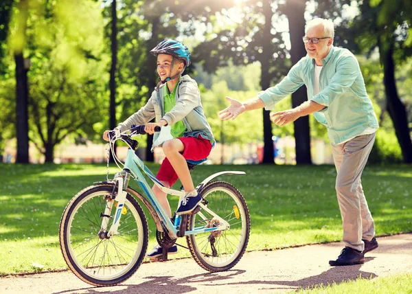 Дедушка и мальчик с велосипедом в летнем парке — стоковое фото