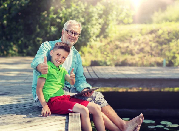 Grandfather and boy with tablet pc on river berth — Stock Photo, Image