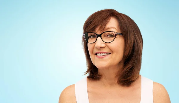 Retrato de mujer mayor en gafas sobre azul — Foto de Stock
