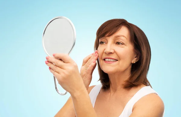 Portrait of smiling senior woman with mirror — Stock Photo, Image