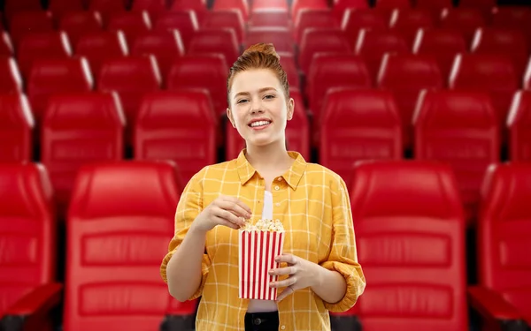 Redhead teenage girl with popcorn at movie theater — Stock Photo, Image