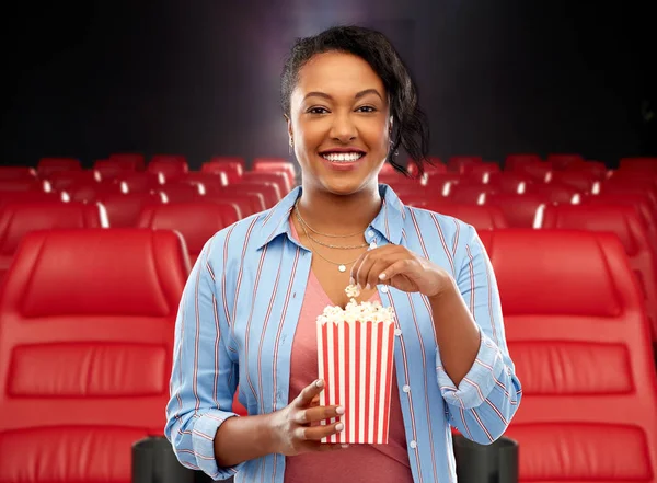 African woman eating popcorn at movie theater — Stock Photo, Image