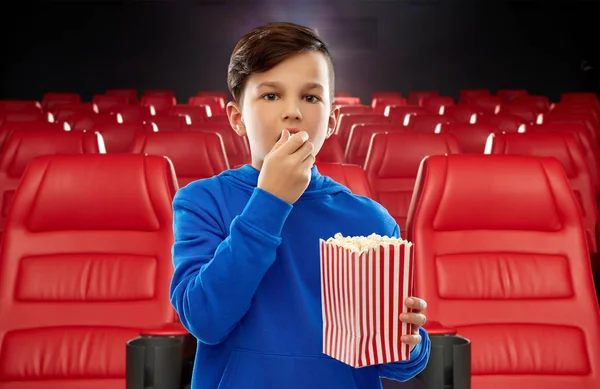 Мальчик в синей толстовке ест попкорн в кинотеатре — стоковое фото