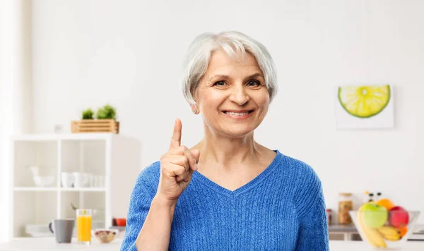Улыбающаяся пожилая женщина, указывающая пальцем на кухню — стоковое фото